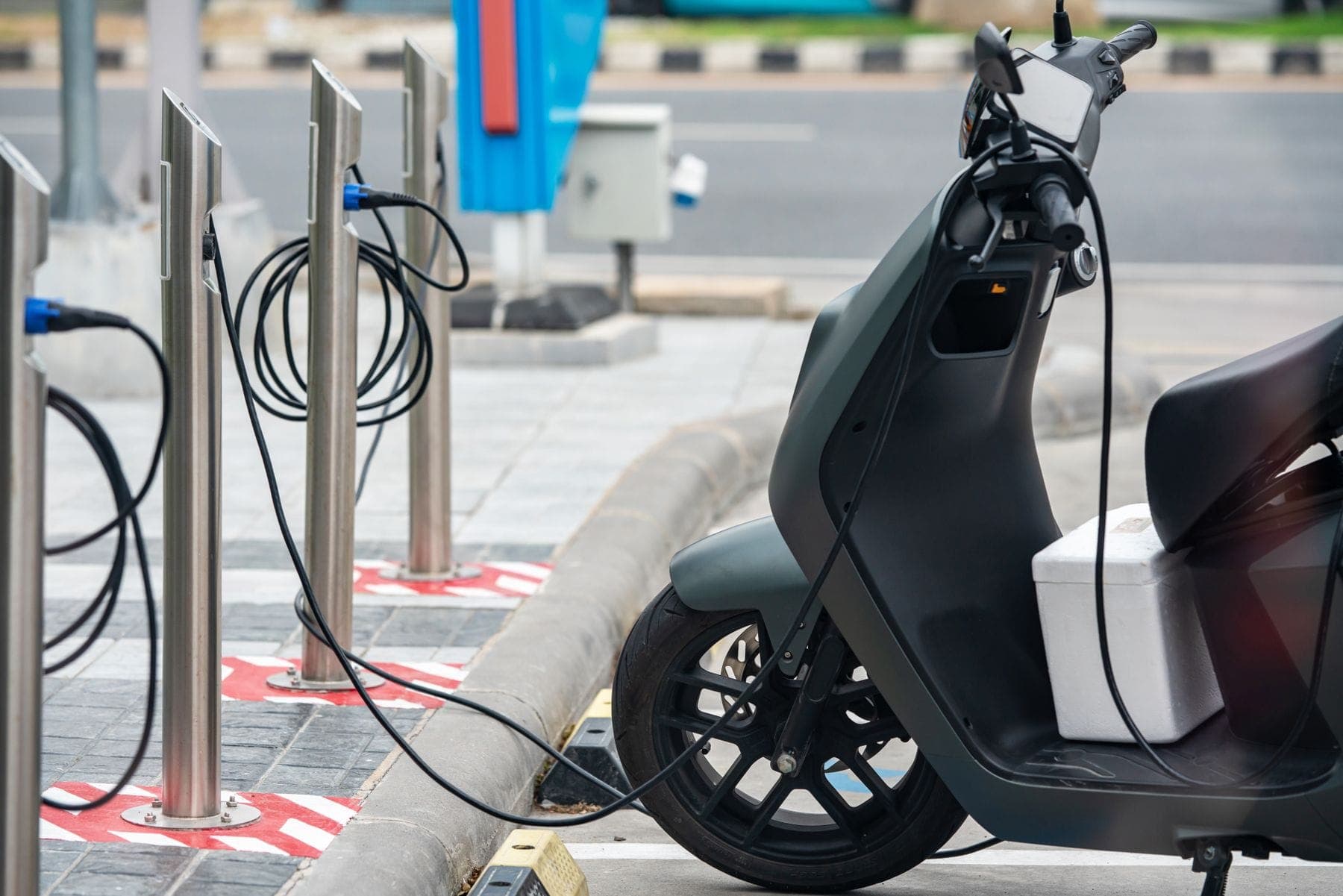 An electric scooter plugged into a street charging point