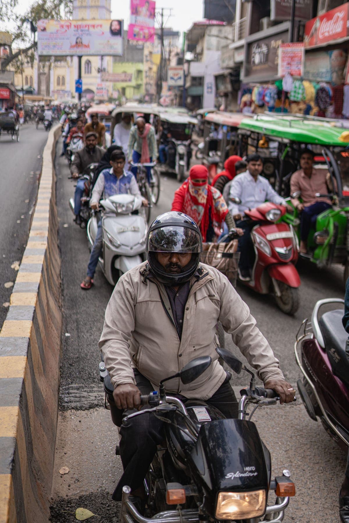 A helmeted rider on a scooter in moving city traffic