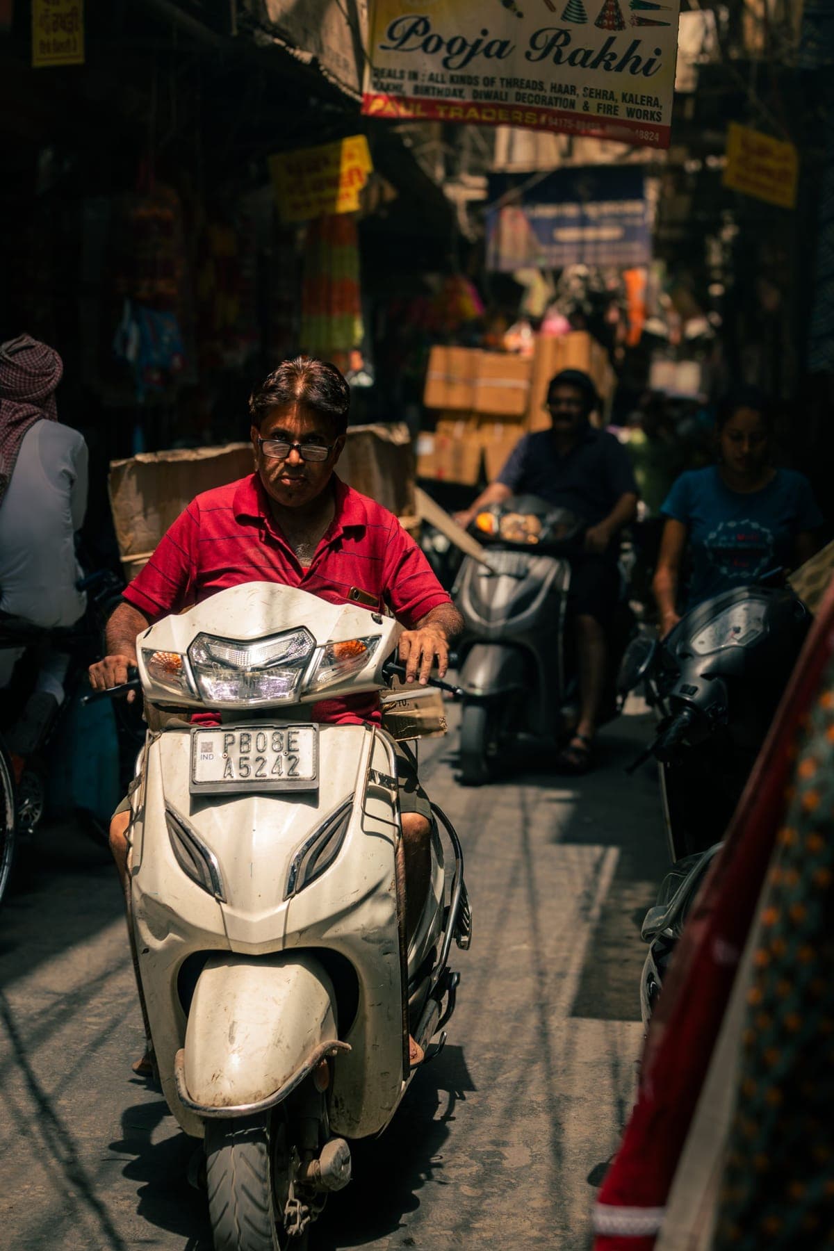 A rider in a red shirt on a scooter on a busy street