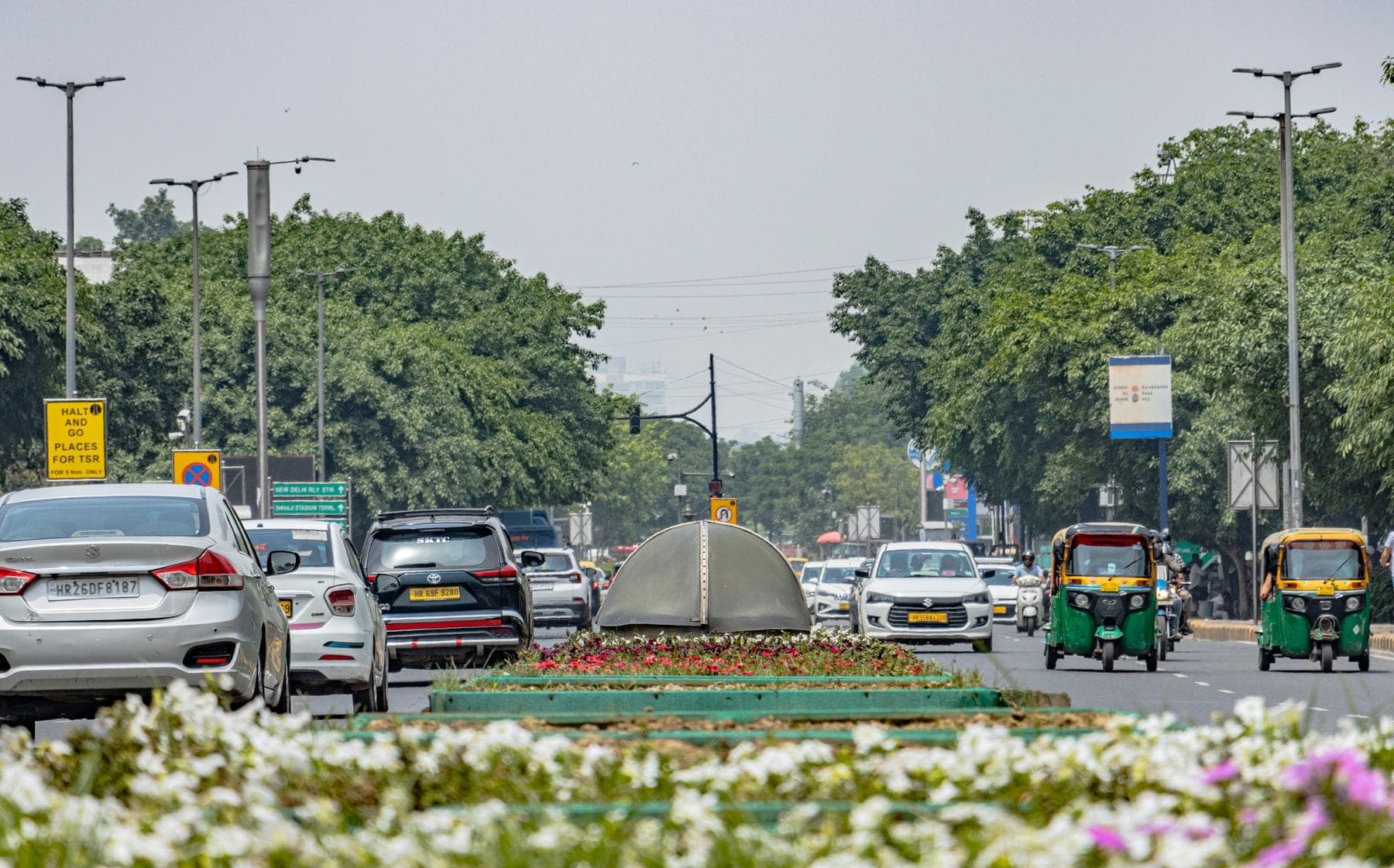A wide Delhi street with autos and cars in daylight