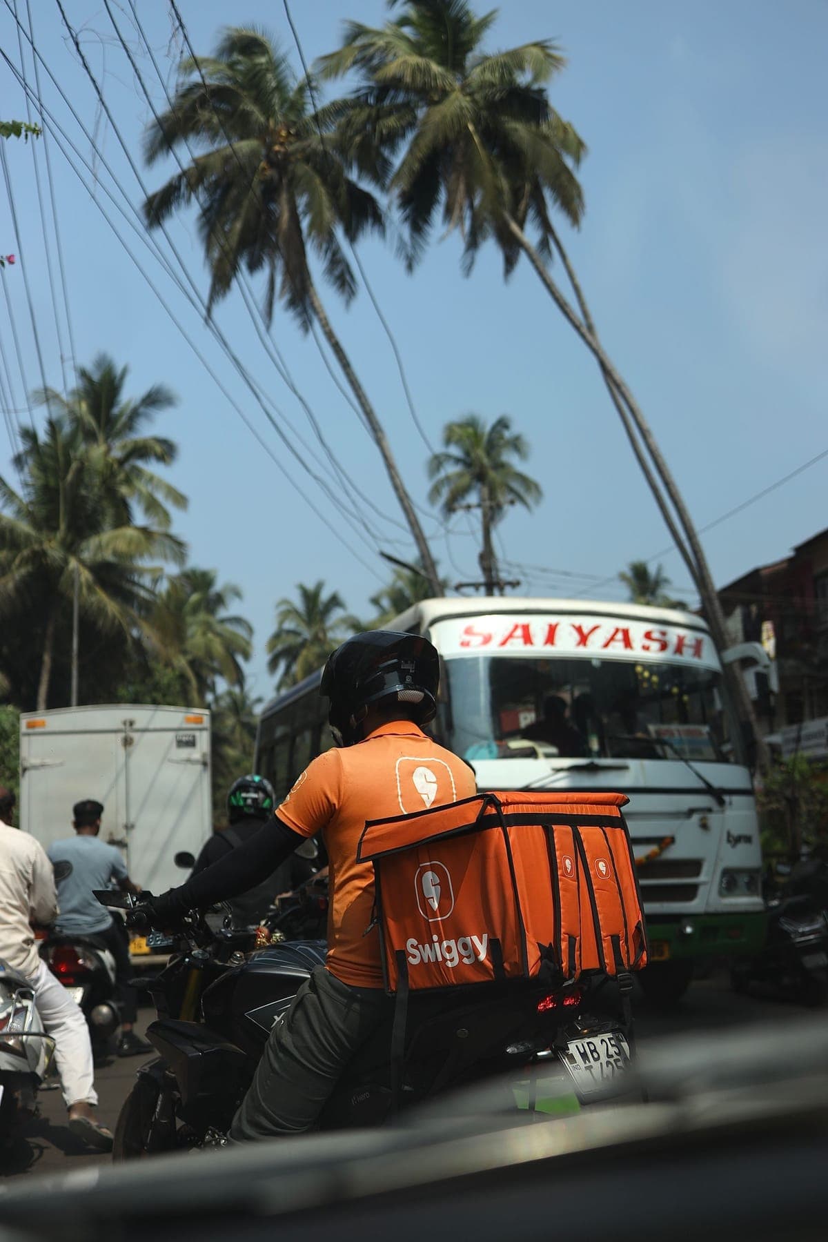 A delivery rider in uniform riding through traffic with an insulated box