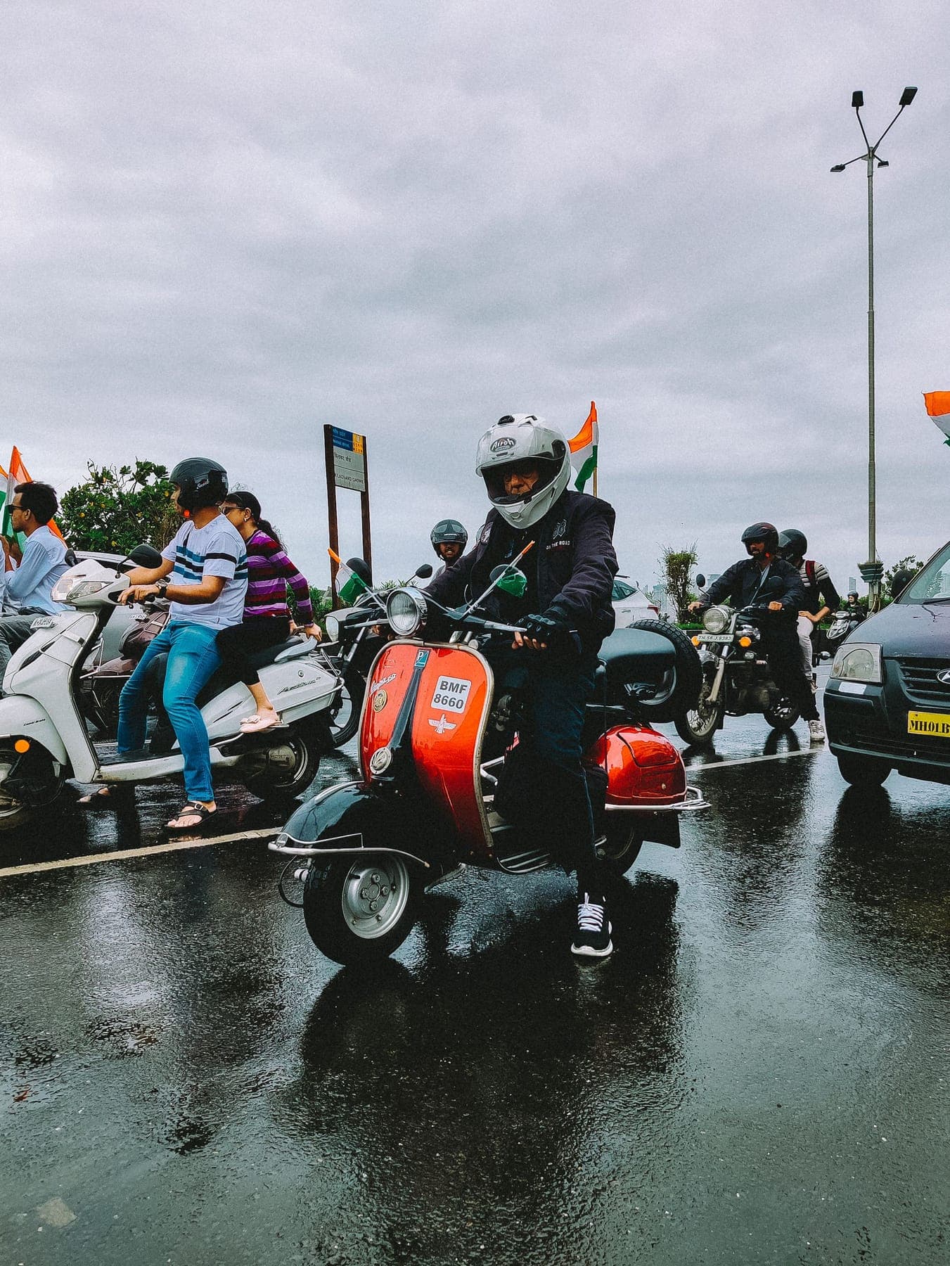 Riders in helmets waiting in traffic on a wet road